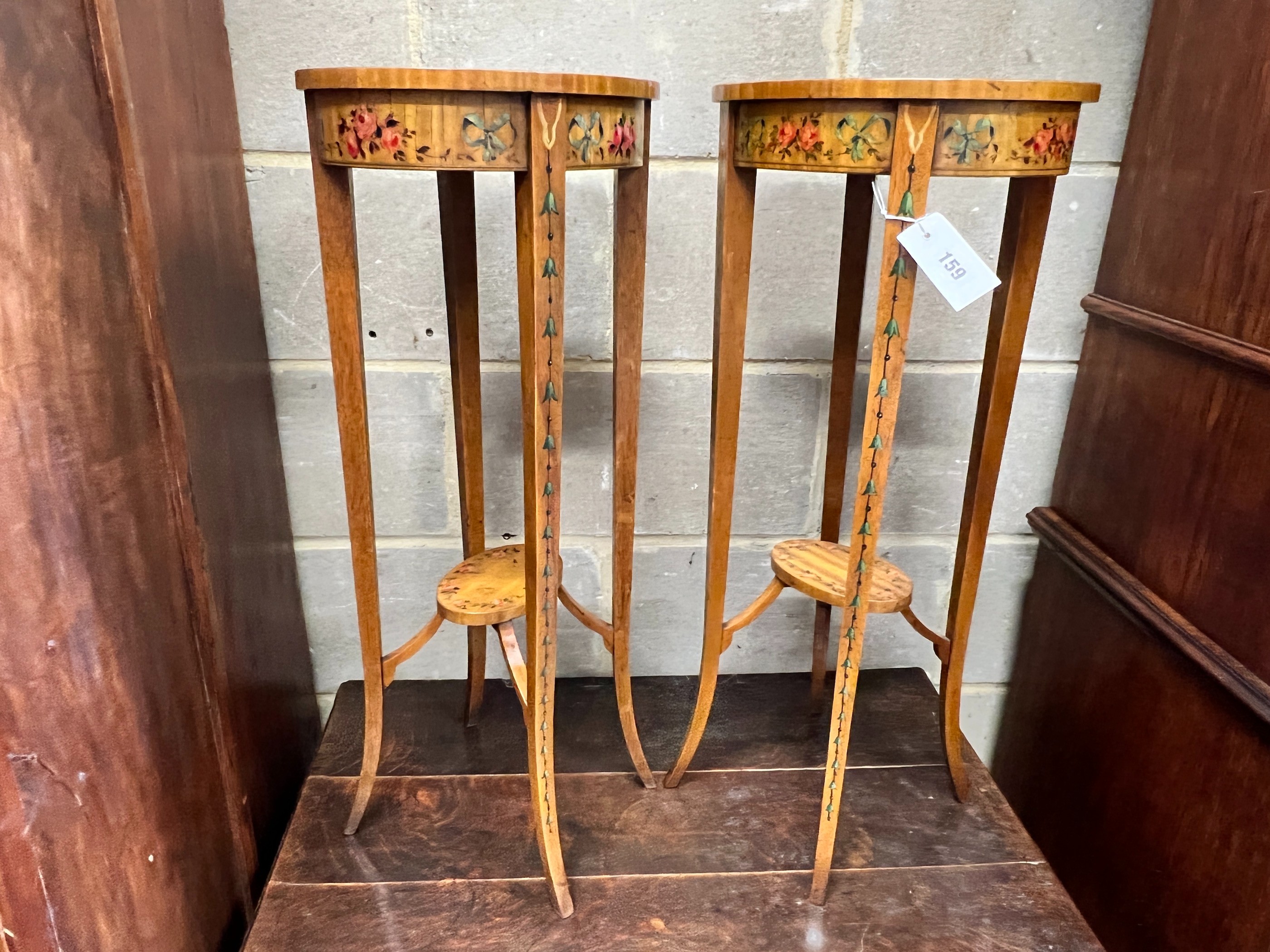 A pair of oval Sheraton style painted satinwood two tier plant stands, width 32cm, depth 26cm, height 71cm